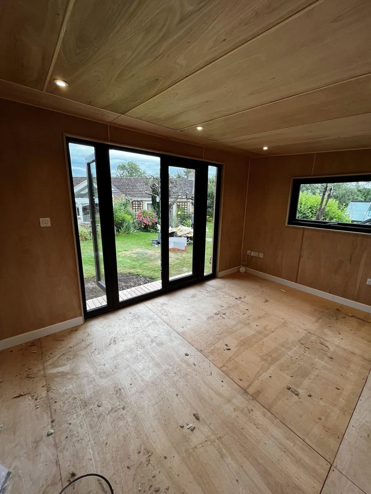 A ply-lined garden room with recessed downlights, a wall socket and glazed doors